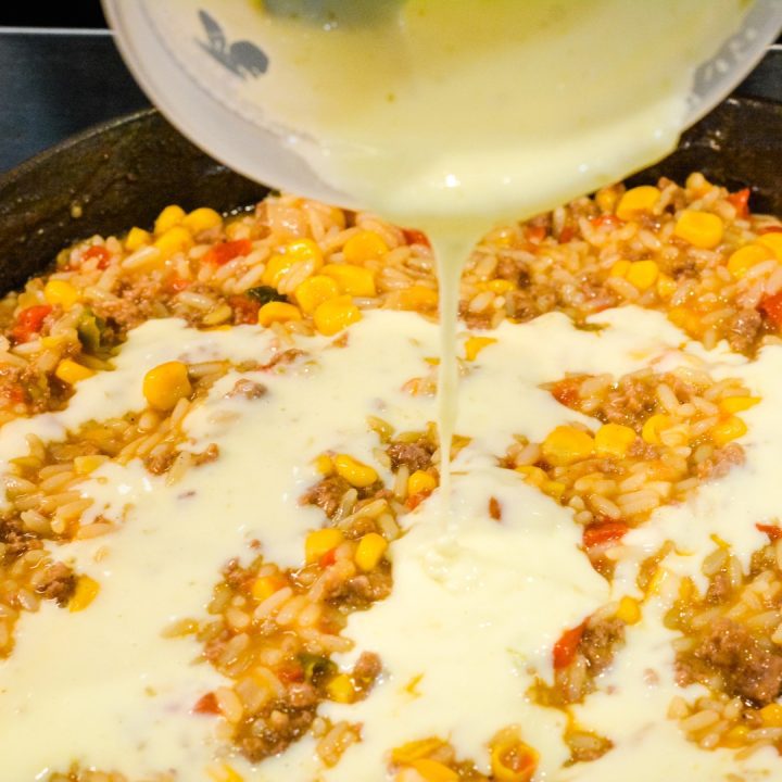 Pour the queso cheese sauce over the top of the rice and beef.