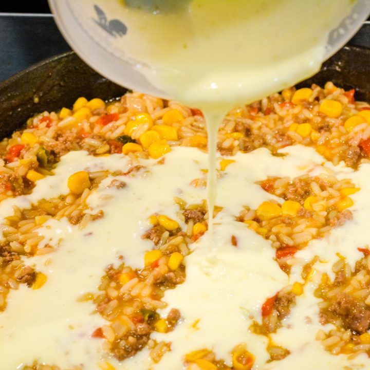 Pour the queso cheese sauce over the top of the rice and beef. 