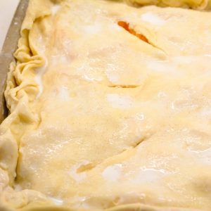 Top with the rolled out remaining pie crust. Crimp the edges. Then brush cream onto the top and sprinkle with a tablespoon of vanilla sugar. Cut 4-6 slits into the pie.