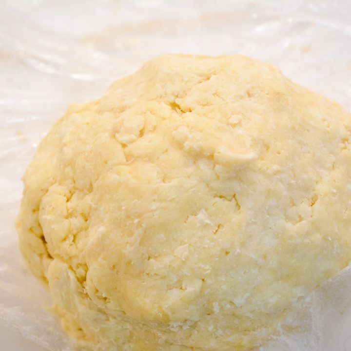 When the butter and flour form pebbles, dump out on a dough mat. Add the egg yolk and ice cold water a tablespoon at a time.