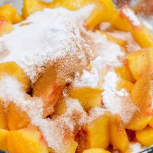 Combine the peaches, bourbon, cornstarch, sugars, and cinnamon in a bowl. Stir together. Set aside and roll out the pie crust dough.