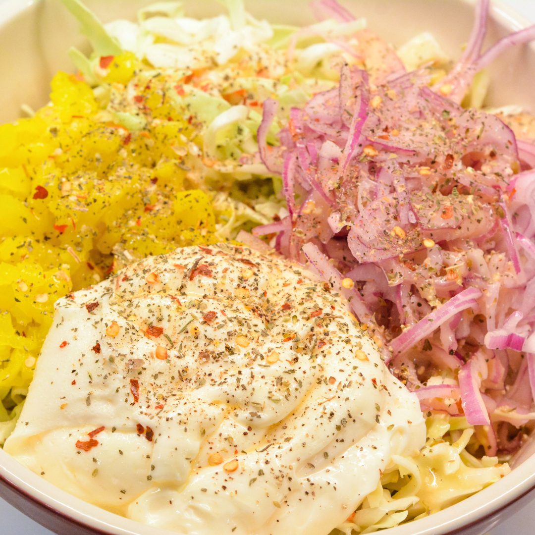 Combine the shredded cabbage, finely sliced onions, and banana rings in