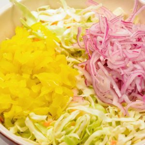 Combine the shredded cabbage, finely sliced onions, and banana rings in a large bowl.