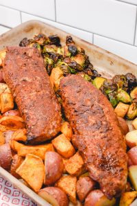 The sheet pan pork tenderloin is rubbed in a sweet and spicy dry rub that is sprinkled on the cut-up sweet potatoes, red potatoes, and Brussels sprouts before it is oven baked.