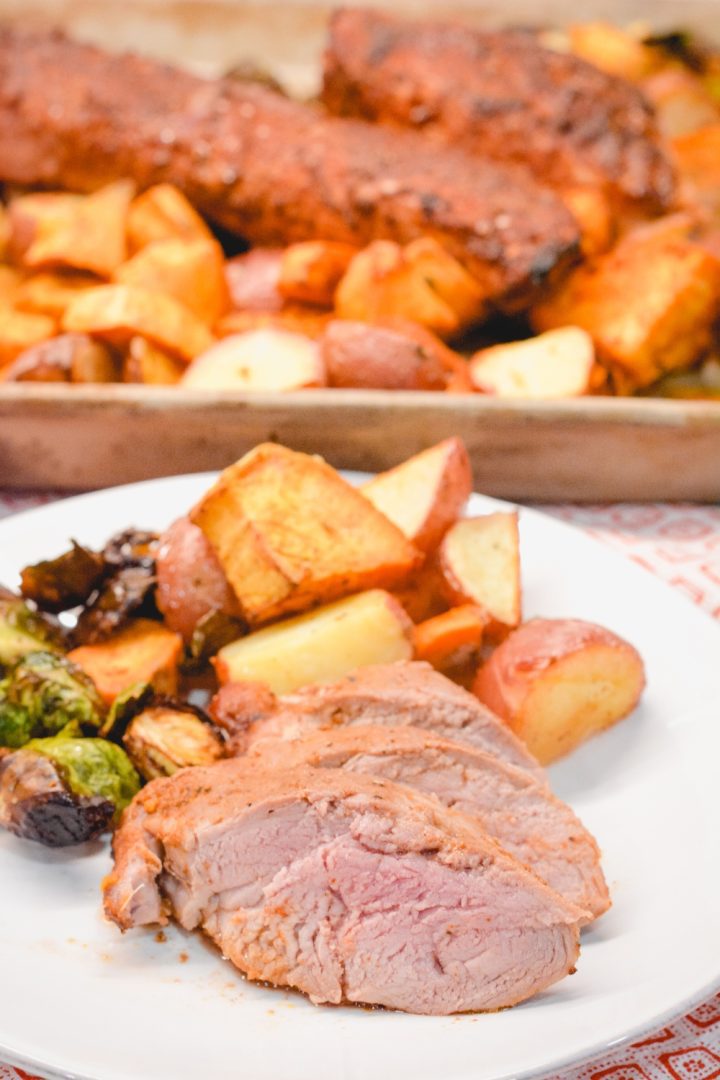 The sheet pan pork tenderloin is rubbed in a sweet and spicy dry rub that is sprinkled on the cut-up sweet potatoes, red potatoes, and Brussels sprouts before it is oven baked.