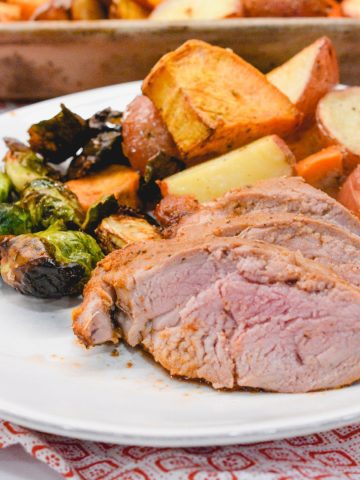 The sheet pan pork tenderloin is rubbed in a sweet and spicy dry rub that is sprinkled on the cut-up sweet potatoes, red potatoes, and Brussels sprouts before it is oven baked.