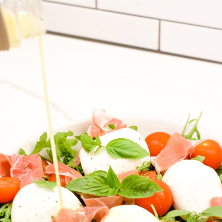 Finish the arugula and prosciutto salad by drizzling the white wine vinaigrette over the top of the arugula salad and serve.