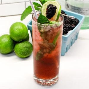 Top off with the mineral water. Garnish with a lime slice, blackberry, and mint leaves.