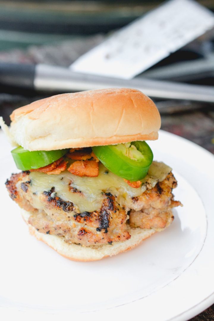 These jalapeno popper stuffed pork burgers are made with ground pork and filled with cream cheese, fresh jalapeno slices, and bacon pieces then topped with even more cheese for the perfect spicy pork burgers recipe.