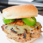 These jalapeno popper stuffed pork burgers are made with ground pork and filled with cream cheese, fresh jalapeno slices, and bacon pieces then topped with even more cheese for the perfect spicy pork burgers recipe.