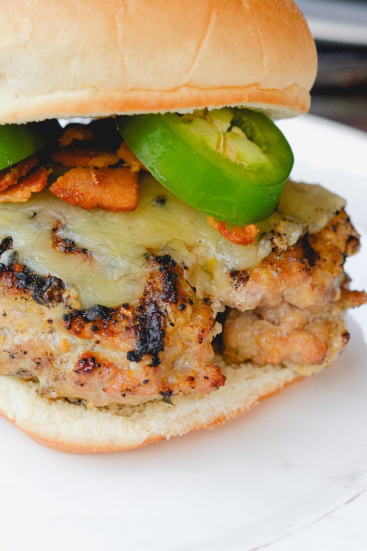 These jalapeno popper stuffed pork burgers are made with ground pork and filled with cream cheese, fresh jalapeno slices, and bacon pieces then topped with even more cheese for the perfect spicy pork burgers recipe.