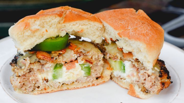 These jalapeno popper stuffed pork burgers are made with ground pork and filled with cream cheese, fresh jalapeno slices, and bacon pieces then topped with even more cheese for the perfect spicy pork burgers recipe.