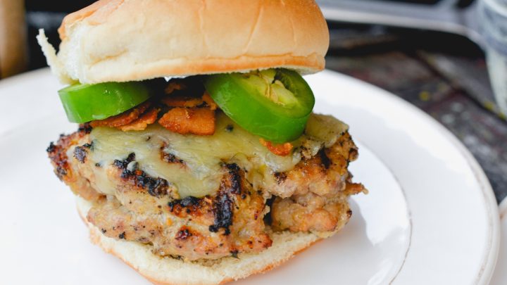 These jalapeno popper stuffed pork burgers are made with ground pork and filled with cream cheese, fresh jalapeno slices, and bacon pieces then topped with even more cheese for the perfect spicy pork burgers recipe.