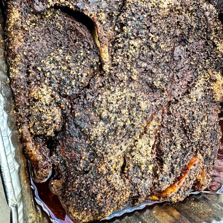 Smoked beef chuck roast will quickly become one of your favorite cuts of beef to smoke with a simple beef rub made with garlic, salt, and pepper and then finished in a pan of onions and beef broth.