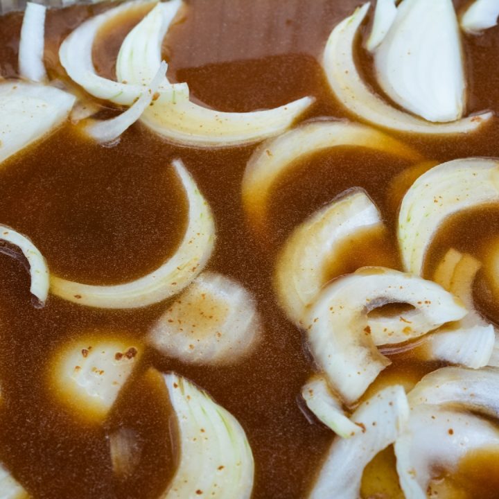 a pan with sliced onions and beef broth.