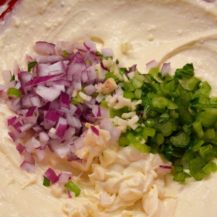 Next add the finely chopped onions, celery, and garlic to the egg salad dressing. Stir to completely combine.