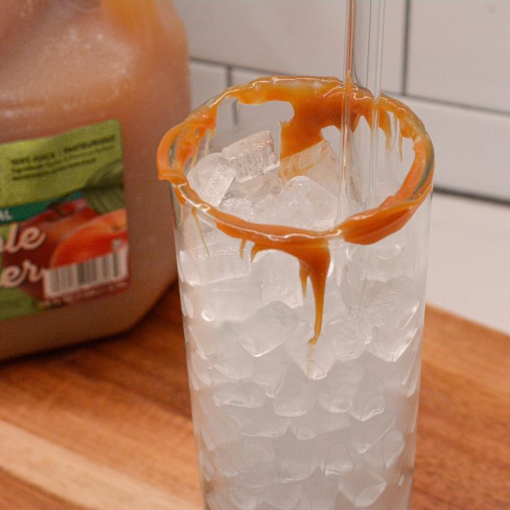 Start by preparing the glass by edging the rim of the glass with caramel sauce. Then fill with ice. 