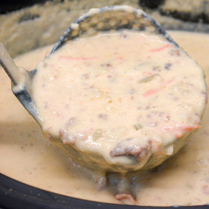 Crock pot bacon cheeseburger soup is potato soup recipe slow-cooked all day in a base of carrots, celery, onions, and garlic along with diced potato hashbrowns, ground beef, bacon, and cream cheese that just needs shredded cheddar cheese and white sauce added before serving for dinner.