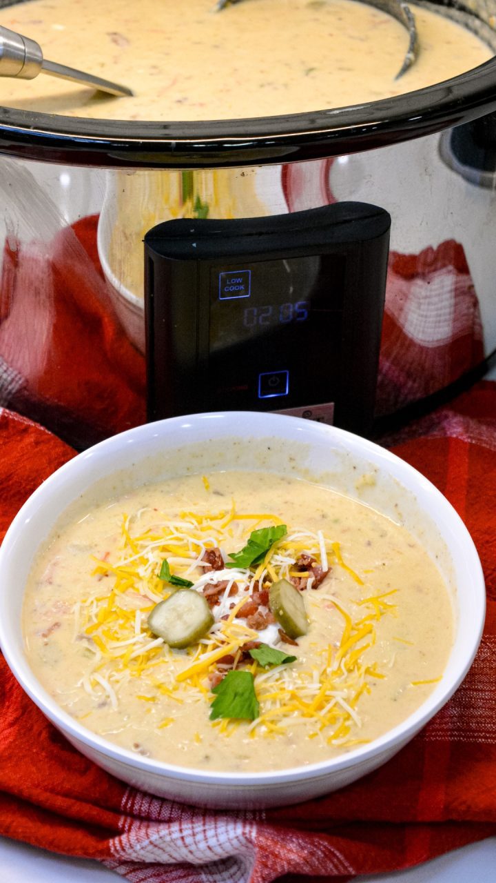 Crock pot bacon cheeseburger soup is potato soup recipe slow-cooked all day in a base of carrots, celery, onions, and garlic along with diced potato hashbrowns, ground beef, bacon, and cream cheese that just needs shredded cheddar cheese and white sauce added before serving for dinner.