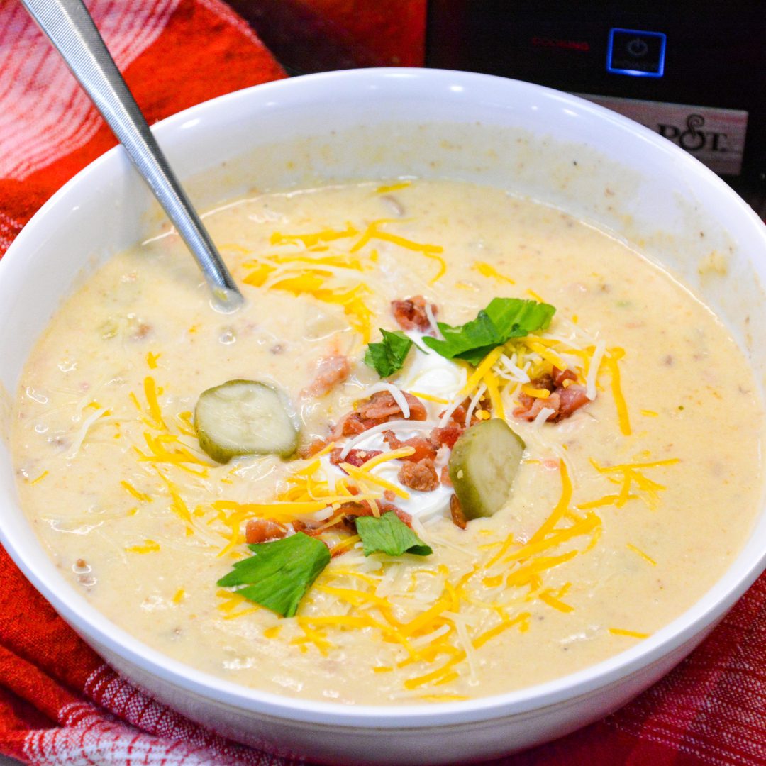 Crock pot bacon cheeseburger soup is potato soup recipe slow-cooked all day in a base of carrots, celery, onions, and garlic along with diced potato hashbrowns, ground beef, bacon, and cream cheese that just needs shredded cheddar cheese and white sauce added before serving for dinner.
