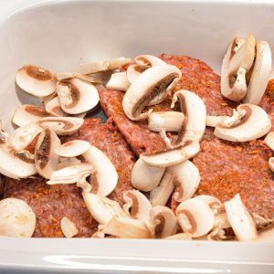 Season the hamburger patties with the steak seasoning. Place in the crock pot in one layer. Then sprinkle half the sliced mushrooms over the patties.