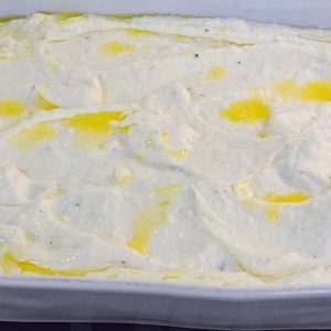 Spread the creamy mashed potato base into a greased casserole dish or 13x9 baking dish. Top off with melted butter.