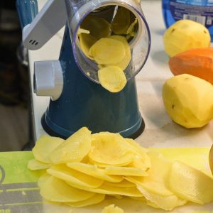 Peel and slice your potatoes. I used a rotary cheese grater and mandoline to slice these potatoes up. Slice onions. Put them in a bowl and season with salt and pepper.
