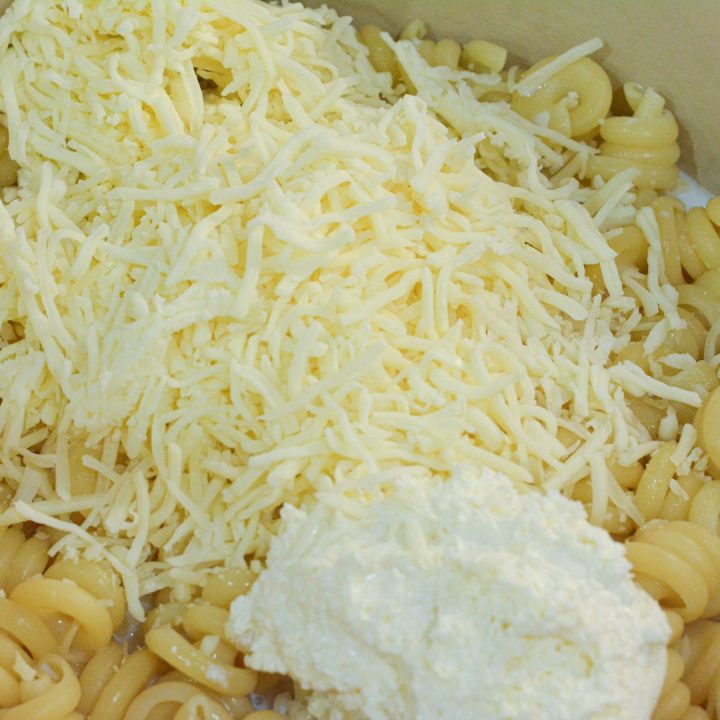 Stir the pasta and butter together to melt the butter, then add the pasta water to the pasta along with the cream cheese, shredded cheese, and milk to make the cheese sauce right with the noodles.