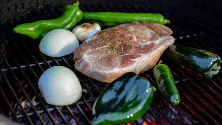 While the pork is smoking, you'll roast poblano and Anaheim peppers, jalapeños, onions, and garlic on the grill to create a zesty green chile sauce. 
