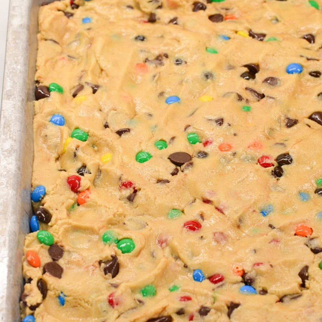 Spread the cookie dough evenly into the prepared baking pan. Sprinkle the remaining 1/2 cup of M&M’s over the top and press them in gently.