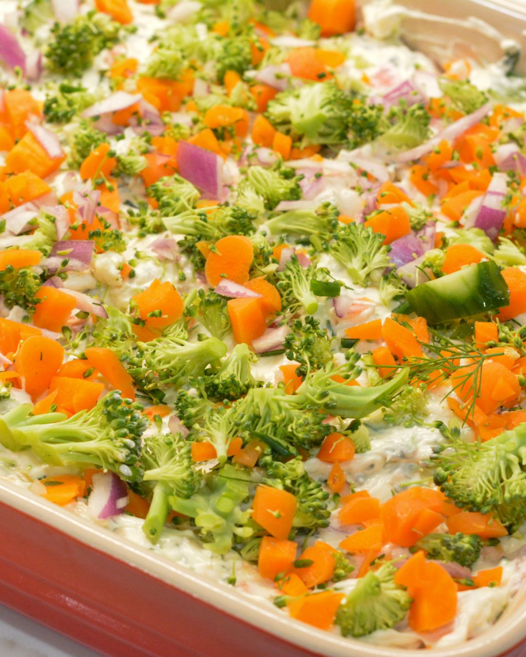 Sprinkle the shredded cheddar cheese evenly over the dip. Then top with the chopped vegetables, pressing them lightly into the dip so they stay put.