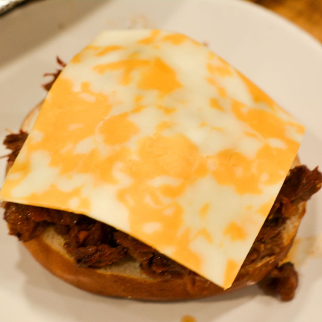 Load shredded beef onto each bun.
Top with Colby Jack cheese, crispy bacon, fried onions, and pickles.
Serve hot with extra barbecue sauce on the side.