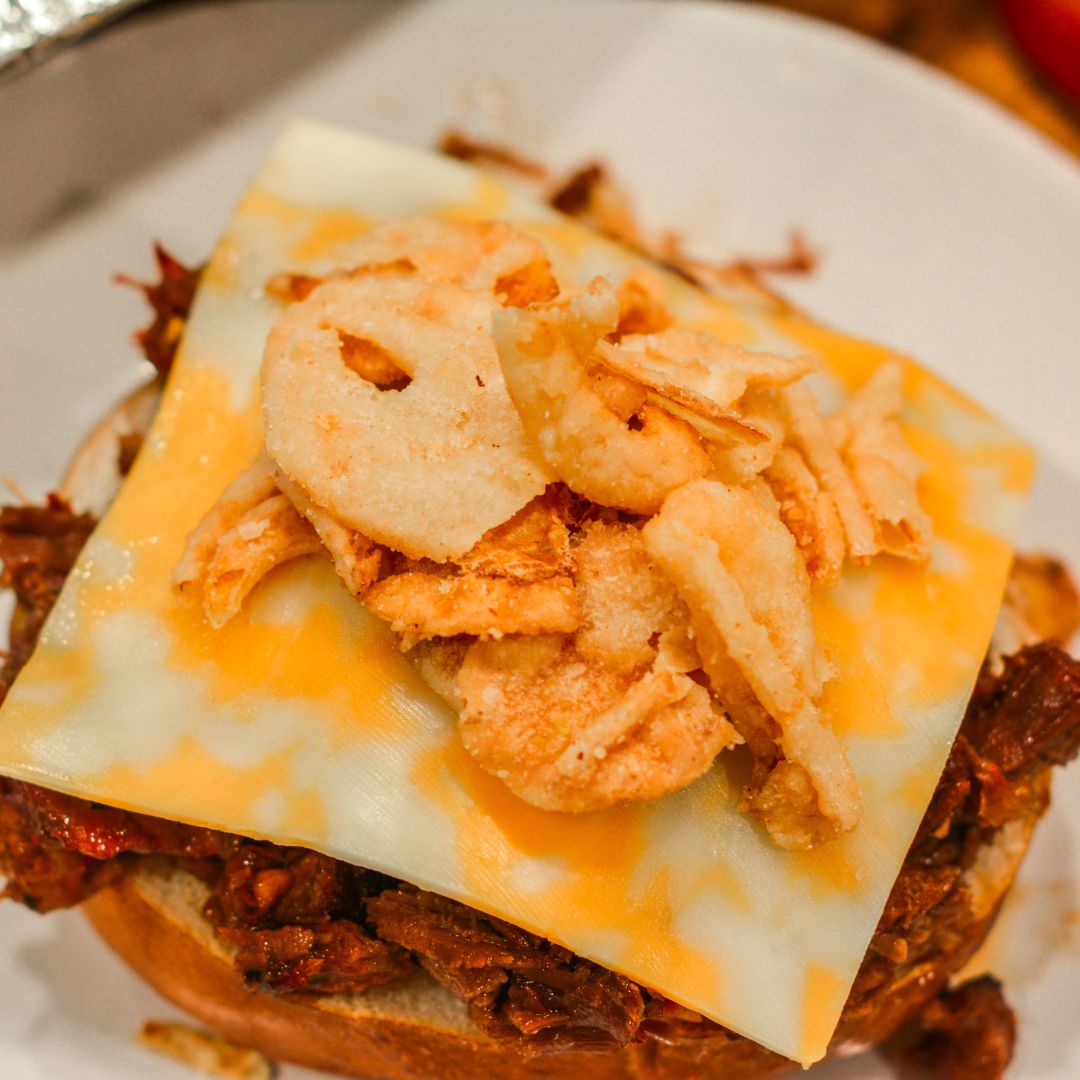 Load shredded beef onto each bun.
Top with Colby Jack cheese, crispy bacon, fried onions, and pickles.
Serve hot with extra barbecue sauce on the side.