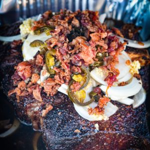 In a large Dutch oven or foil pan, combine barbecue sauce, beef broth, Coca-Cola, Worcestershire sauce, sliced onion, garlic, jalapeños, and bacon.