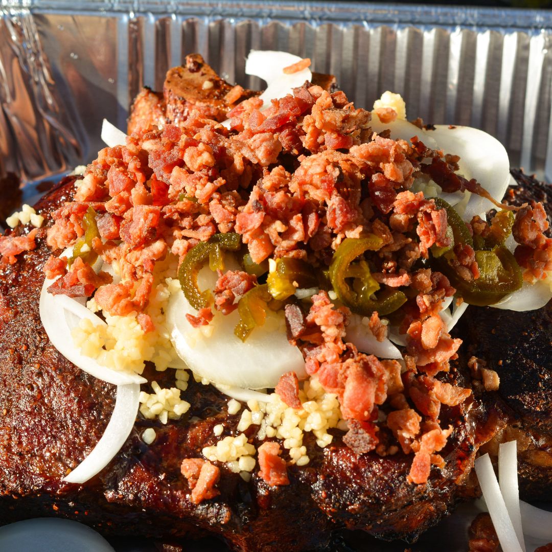 In a large Dutch oven or foil pan, combine barbecue sauce, beef broth, Coca-Cola, Worcestershire sauce, sliced onion, garlic, jalapeños, and bacon.
