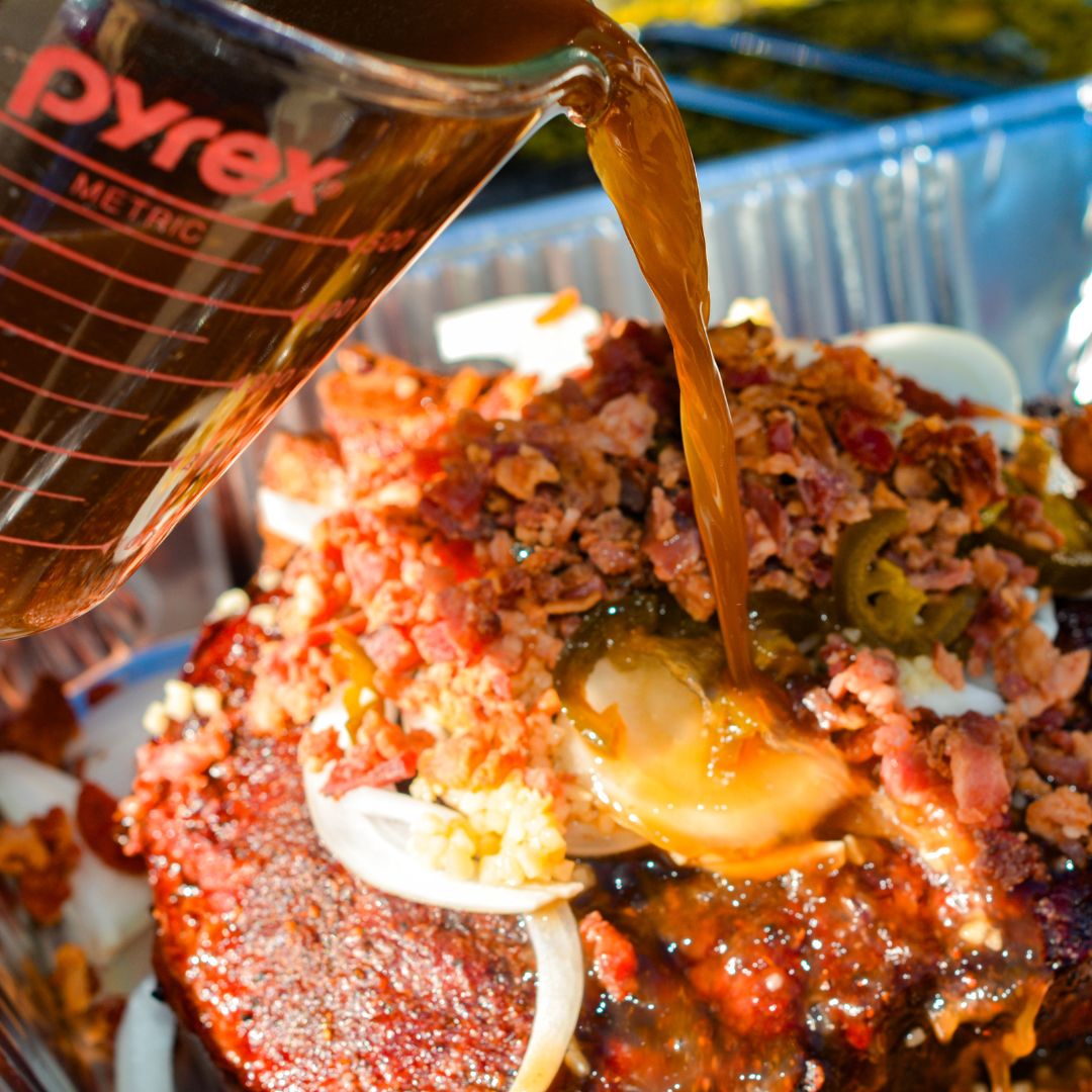 In a large Dutch oven or foil pan, combine barbecue sauce, beef broth, Coca-Cola, Worcestershire sauce, sliced onion, garlic, jalapeños, and bacon.