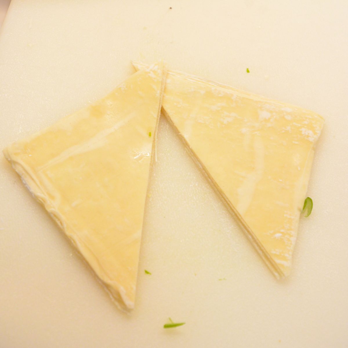 Slice each wonton wrapper into triangles or strips using a sharp knife or pizza cutter.