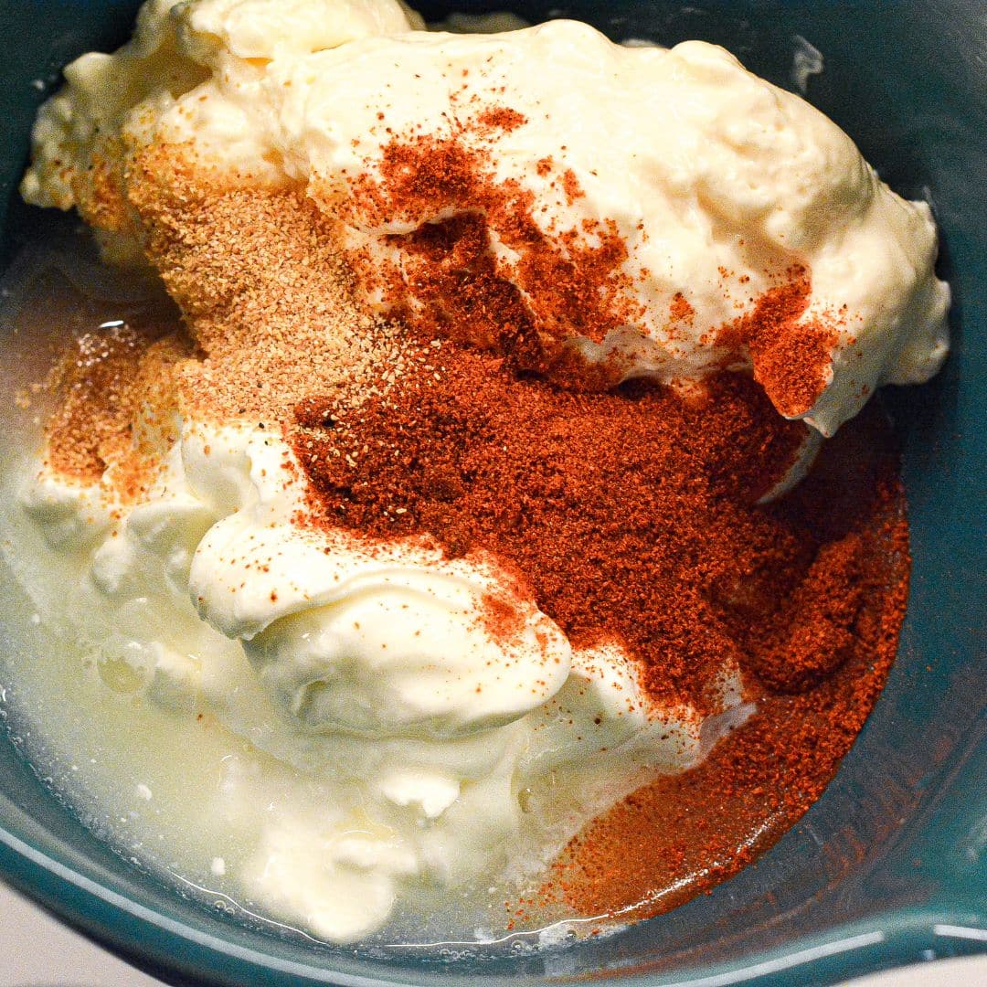 Mayonnaise and sour cream topped with smoked paprika and chipotle powder in a mixing bowl