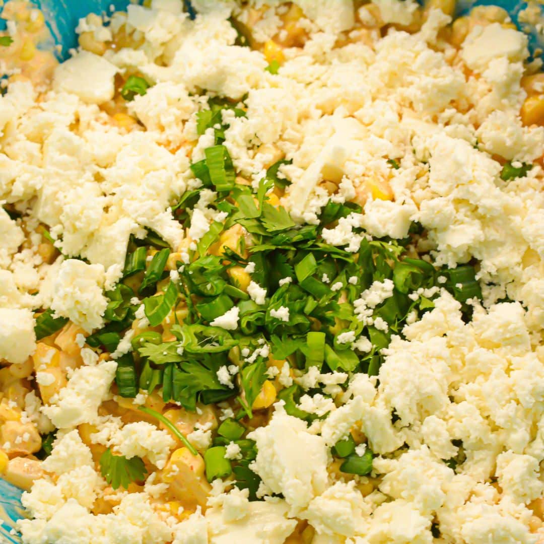 Crumbled queso fresco, green onion, and cilantro added to street corn salad