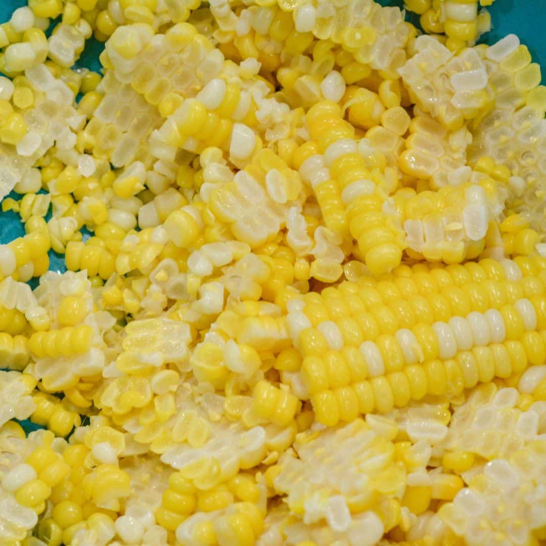 Fresh corn kernels cut off the cob in a teal mixing bowl