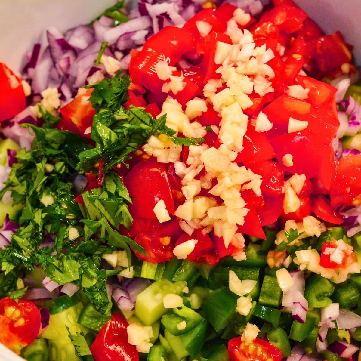 Chopped tomatoes added to cucumber, onion, and jalapeño for cucumber salsa