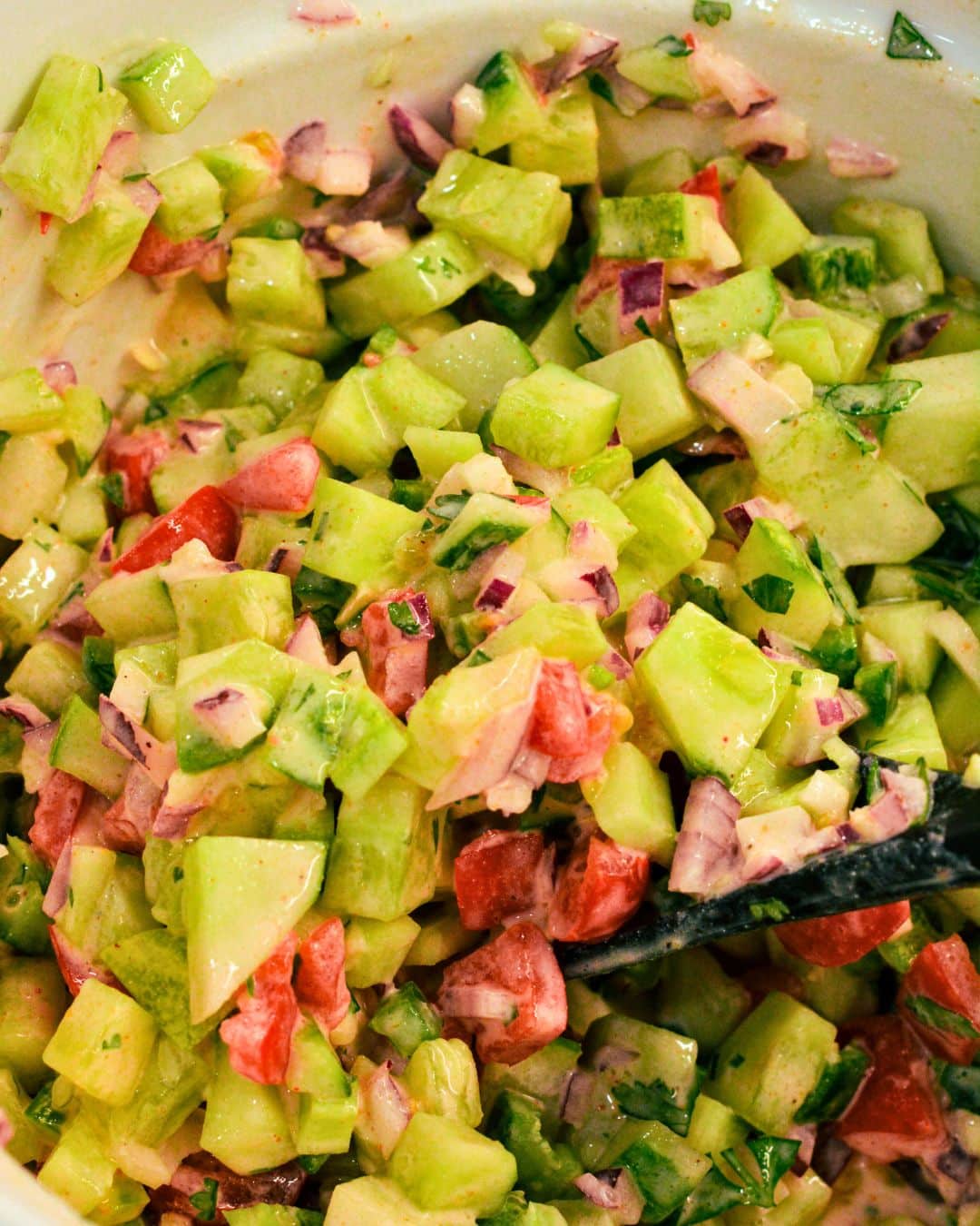 Spoon scooping fresh cucumber salsa for serving with chips
