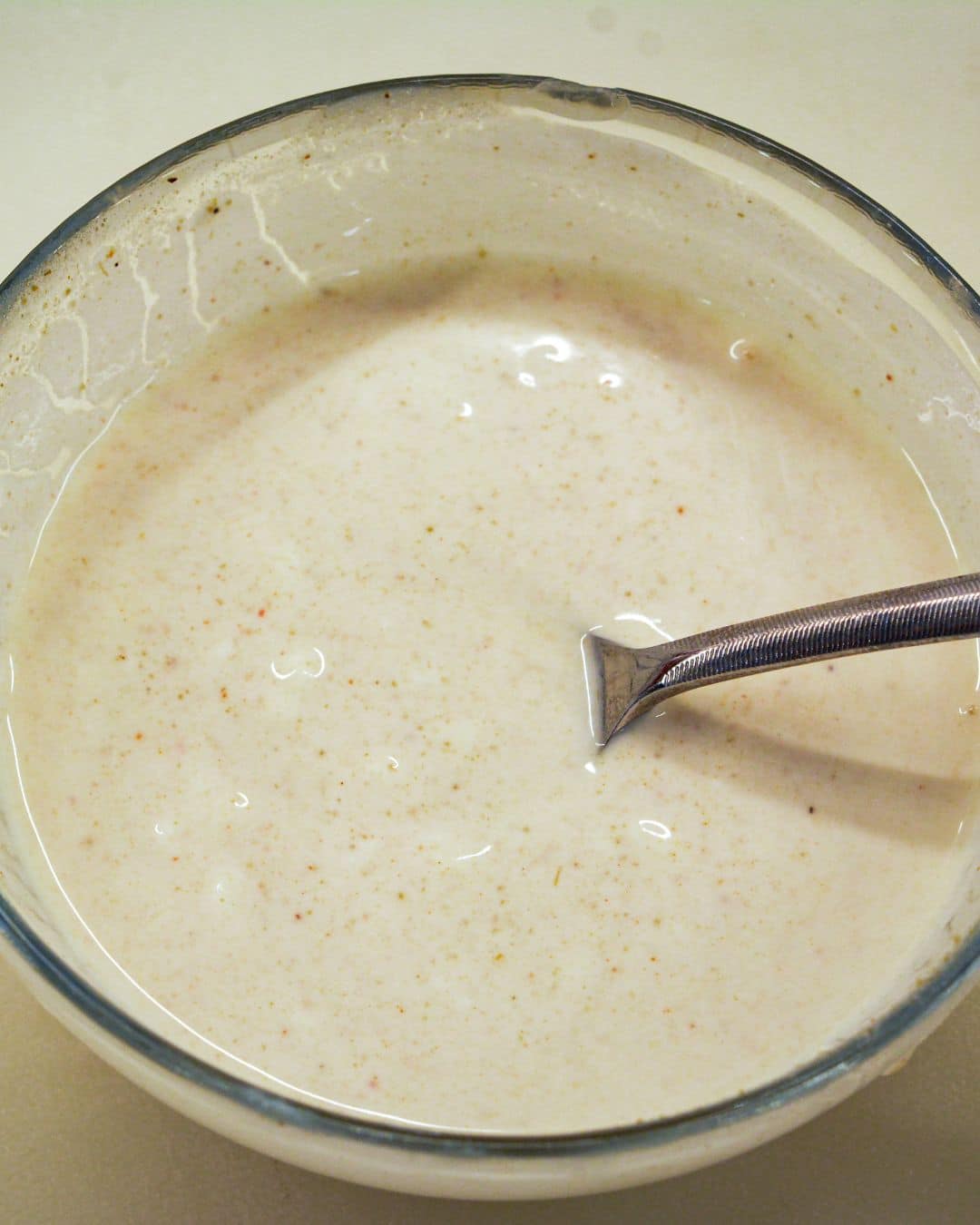 Creamy sour cream and lime dressing whisked together in a glass bowl