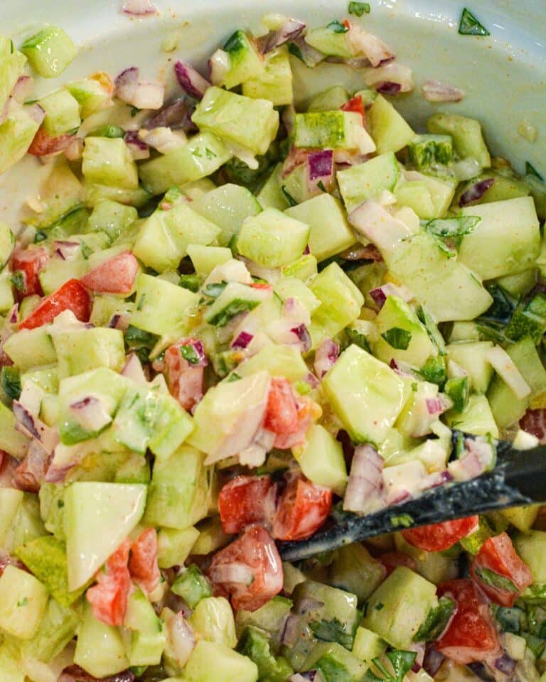Spoon scooping fresh cucumber salsa for serving with chips